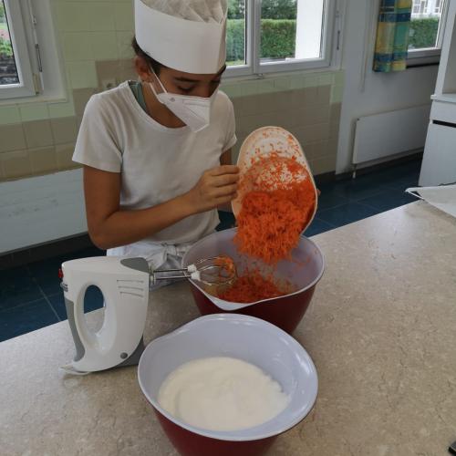 Eine Schülerin gibt Karotten in eine Schüssel