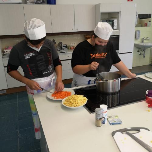 Ein Schüler und eine Schülerin bereiten eine Gemüsesuppe zu
