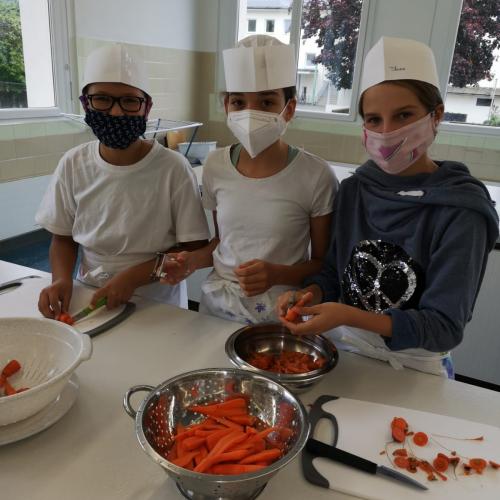 Ein Schüler und zwei Schülerinnen schälen Karotten