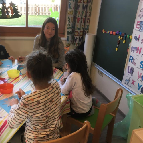 Schülerinnen mit Volksschülern am Tisch sitzend