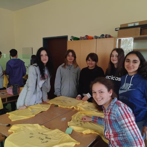 Gruppenfoto der Schüler:innen mit den bedruckten T-Shirts am Tisch. 