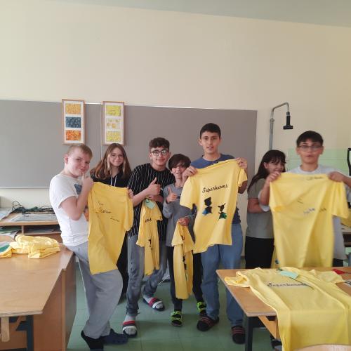 Schüler:innen zeigen ihre gelben bedruckten T-Shirts.