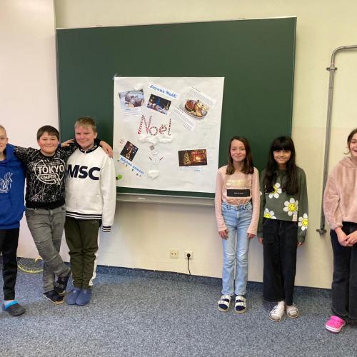 Schülerinnen der unverbindlichen Übung Französisch präsentieren ihr Plakat zu den französischen Weihnachtstraditionen.