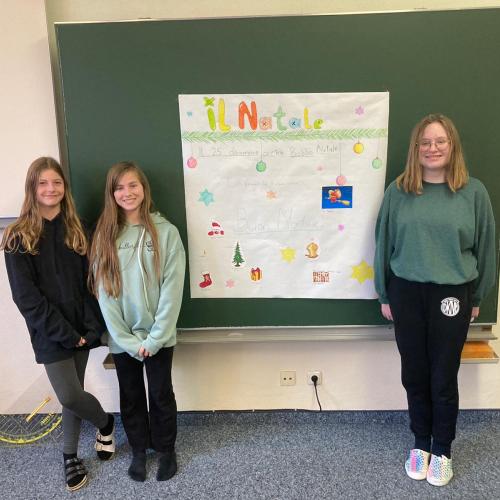 Schülerinnen der unverbindlichen Übung Italienisch präsentieren ihr Plakat zu den italienischen Weihnachtstraditionen.