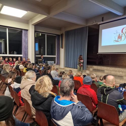 Eltern und Schüler:innen lauschen den Eröffnungsworten der Direktorin