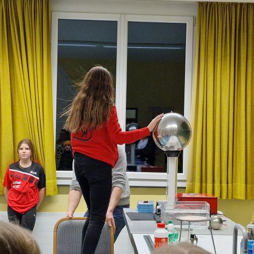 Eine Schülerin bei einem Physikexperiment mit Strom. 