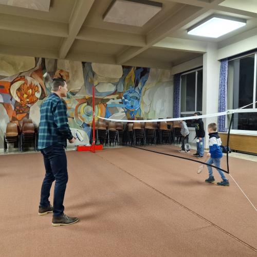 Ein Elternteil und ein Kind probieren Badminton in der Aula.