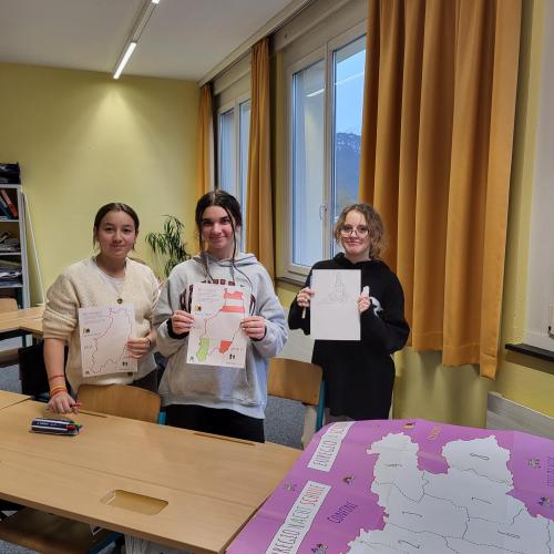 Schülerinnen zeigen ihre gestalteten Puzzleteile. 