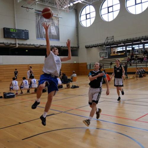 Schüler beim Sprung und Wurf zum Korb. 