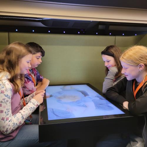 Schülerinnen und Schüler sitzen am großen Tablet