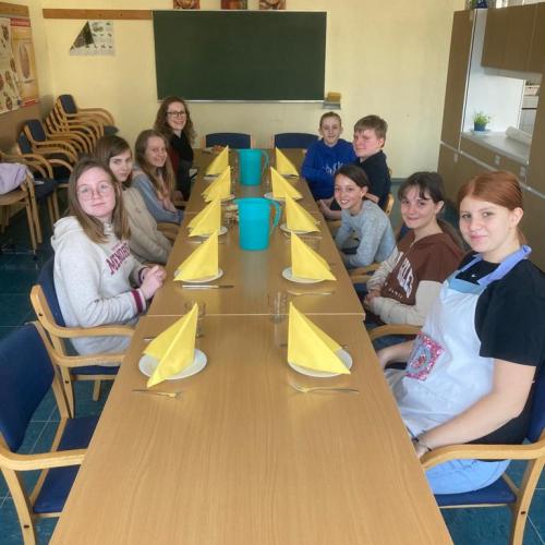 Schüler:innen am gedeckten Tisch. 