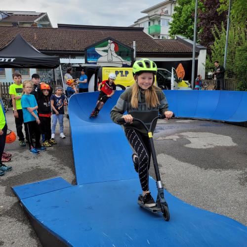 Schüler und Schülerin fahren mit dem Scooter im Pumptrack.