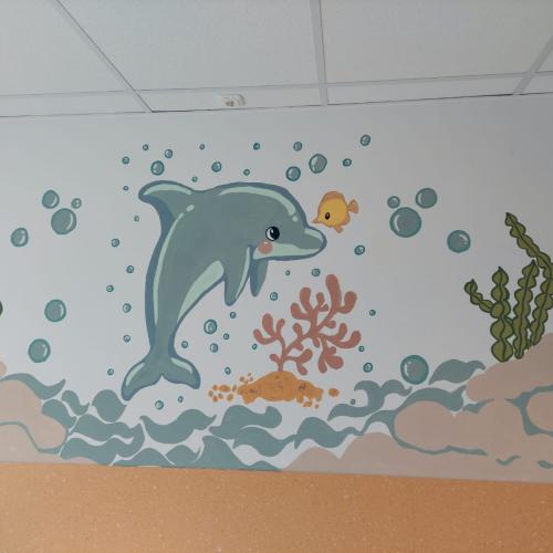 Gemalter Delphin in der Unterwasserwelt an einer Wand eines Kinderkrankenzimmers.