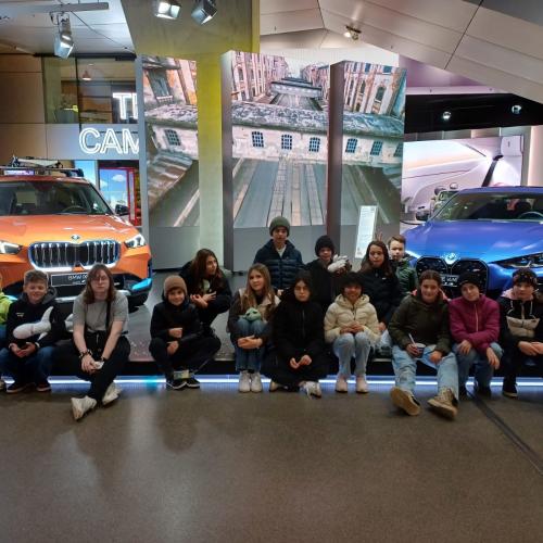 Gruppenfoto der 2b vor zwei Autos im Automuseum. 