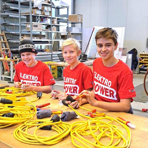 Drei Schüler arbeiten mit Elektrokabeln im EW Reutte.