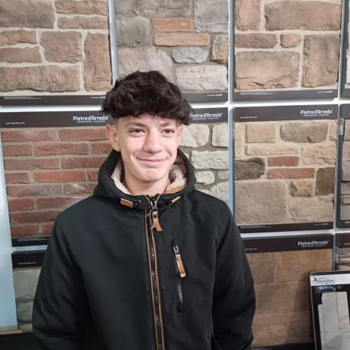 Schüler vor einer Mauer mit unterschiedlichen Steinformen.