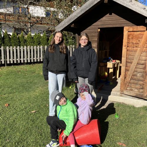 Zwei Schülerinnen im Kindergarten Höfen sind mit zwei Kindern im Garten spielen. 