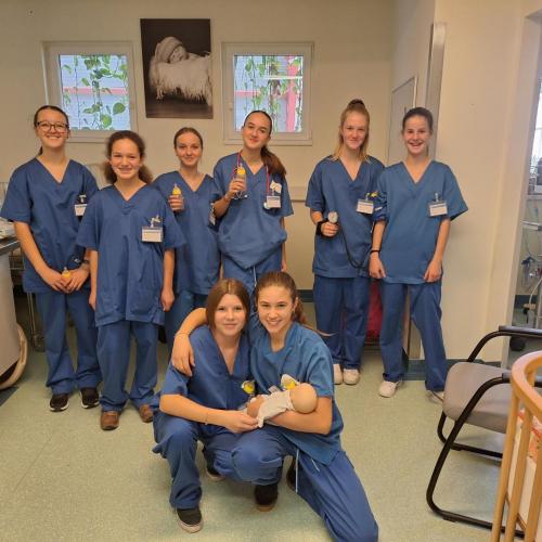 Gruppenfoto von 8 Schülerinnen im BKH Reutte. Alle tragen die blaue Arbeitskleidung einer Krankenschwester.