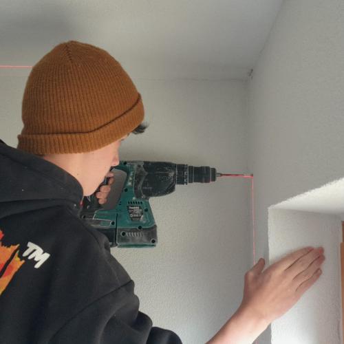 Ein Schüler bohrt in eine Wand.