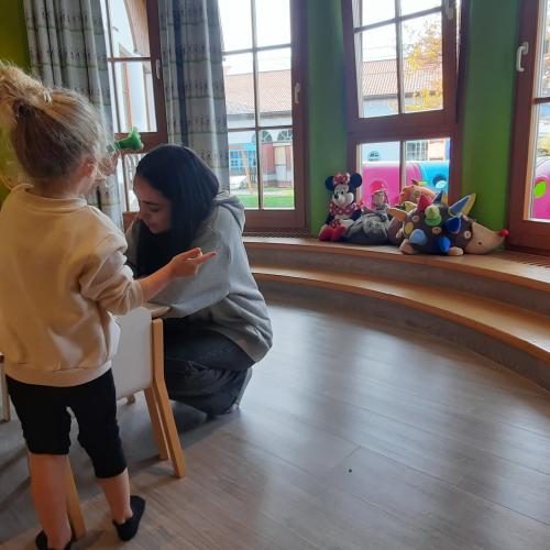 Eine Schülerin spielt mit einem Kindergartenkind.