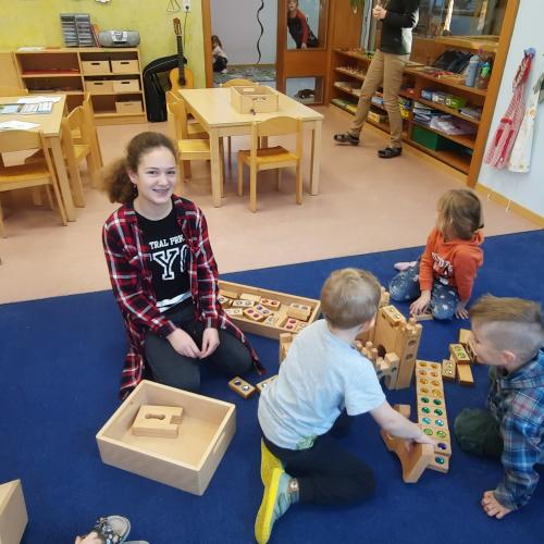 Eine Schülerin spielt mit Kindern im Kindergarten.