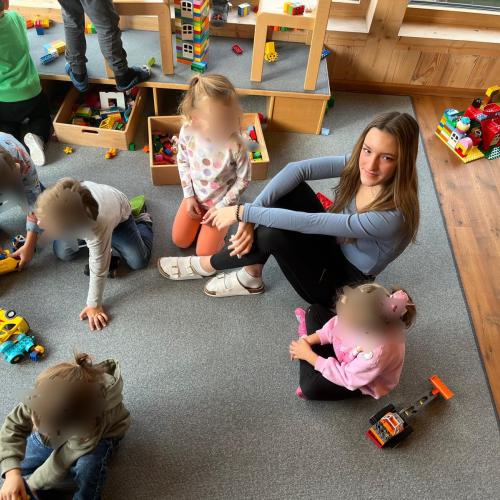 Eine Schülerin spielt mit Kindern im Kindergarten.