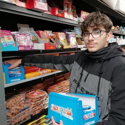 Ein Schüler räumt Regale im Zengin Supermarkt ein. 