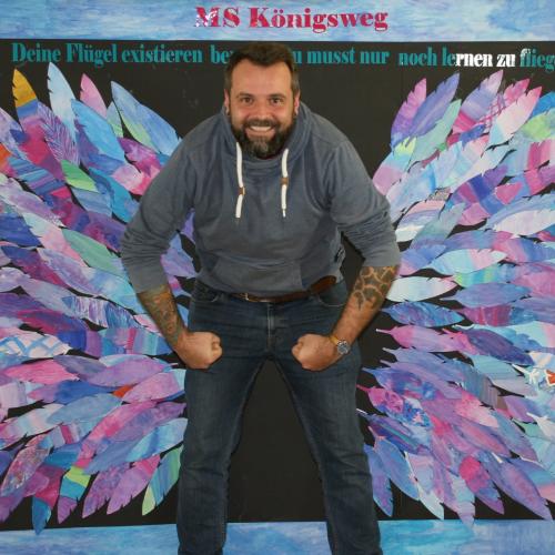 Ein Erwachsener vor der Fotowand des WPF Kreativ. 