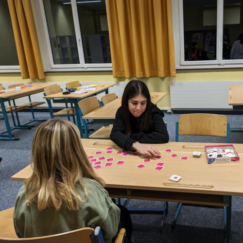 Eine DaZ-Schülerin spielt ein Spiel mit einem Volksschulkind. 