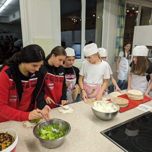 Foto der Schüler:innen, die in der Küche Köstlichkeiten herrichten. 