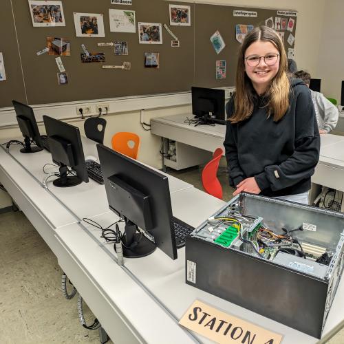 Eine Schülerin zeigt einen offenen Computer. 
