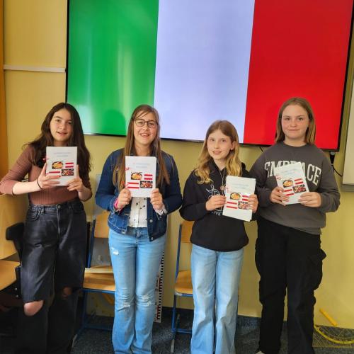 Schüler:innen der 1c zeigen ihr fertiges Kochbuch, dass alle Italienischschüler:innen gemeinsam gemacht haben.