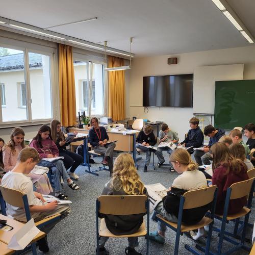 Schüler:innen in einem Sitzkreis mit ihrem Lehrer.