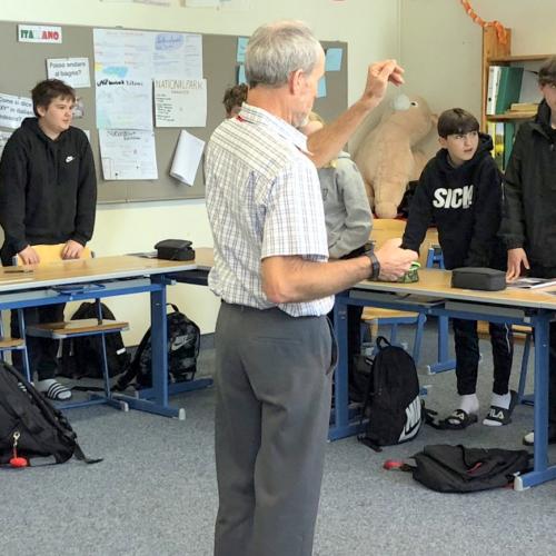 Schüler stehen in einer U-Form und die Lehrperson erklärt etwas.