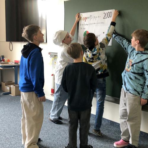 Schüler hängen ihr Plakat auf die Tafel.