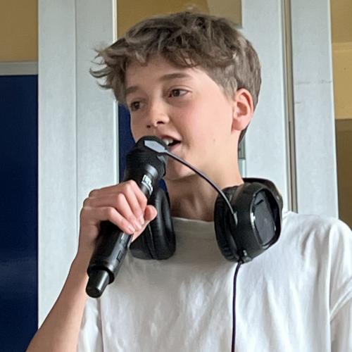 Ein Schüler mit Mikrofon auf der Bühne bei den Abschlusspräsentationen.