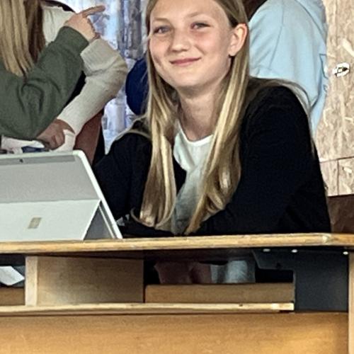 Eine Schüler arbeitet am Tablet und lacht in die Kamera.