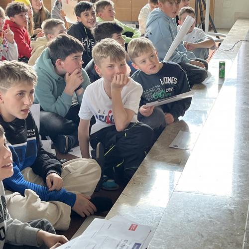 Die Schüler lauschen aufmerksam den Abschlusspräsentationen in der Aula.