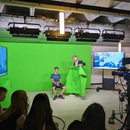 Besuch der ORF. Schüler mit Moderator vor dem Greenscreen.