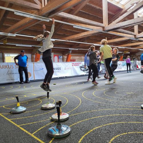 Eine Schülerin springt beim Jubeln in die Luft, da sie einen Volltreffer beim Stocksport gelandet hat.