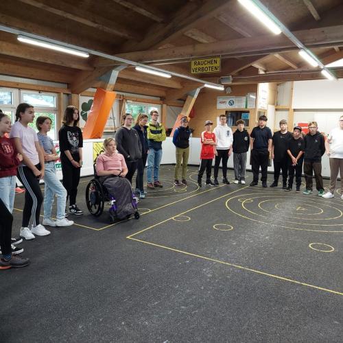 Schüler:innen lauschen den Erklärungen des Stockschieß Trainers.