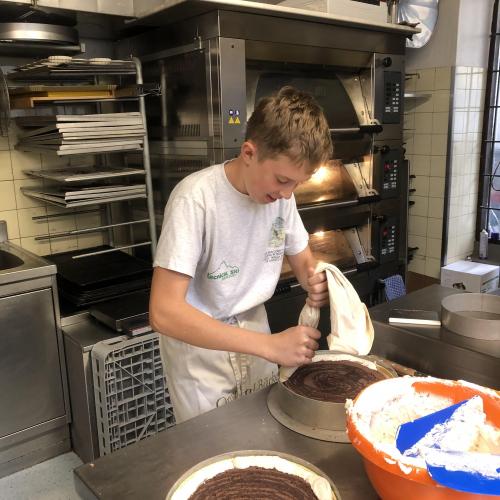 Schüler bei der Konditorei Valier beim Dekorieren einem Kuchen.