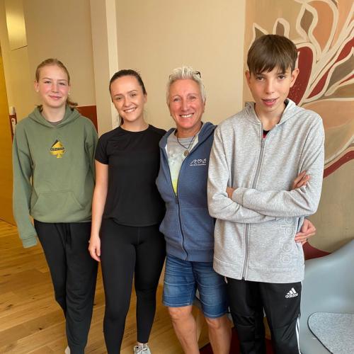 Drei Schüler:innen stehen neben ihre Betreuerin biem Schnuppern in einer Physiotherapie.