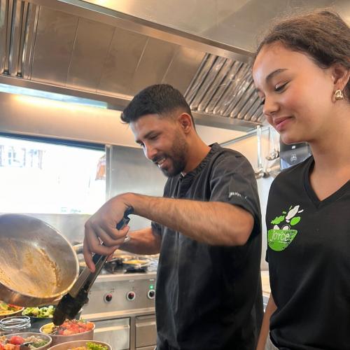 Eine Schülerin bereitet mit einem Koch ein Gericht im Joyce zu. 