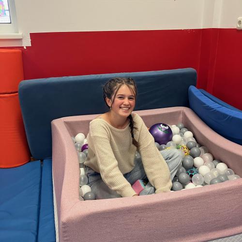 Eine Schülerin sitzt im Bällebad bei dem Mühlmäusen.