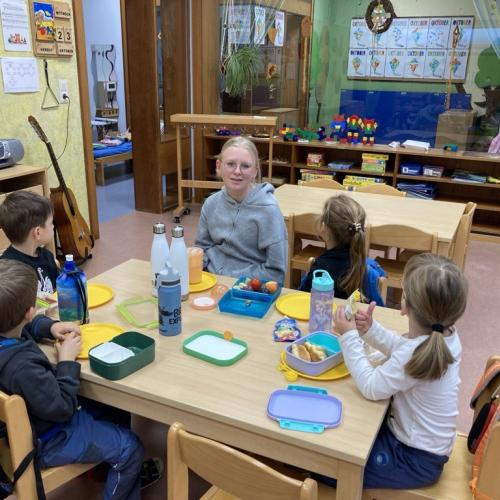 Eine Schülerin sitzt mit Kindern am Tisch im Kindergarten Heiterwang.