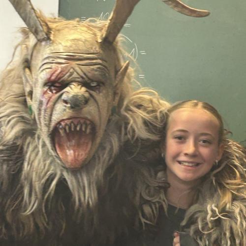 Ein Krampus hat eine Schülerin im Arm.