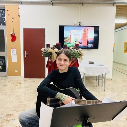 Schülerin mit der Gitarre im Eingangsbereich, bereit uns etwas vorzuspielen.
