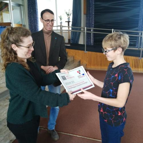 Lehrperson übergibt im Beisein der Bürgermeisters von Reutte die Plakette.