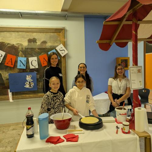 Lehrpersonen mit Schülern beim Vorbereiten der Crepes beim Französischstand.